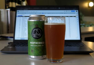 A can of 8 Wired 'Hopwired' IPA in front of a laptop with a spreadsheet on screen